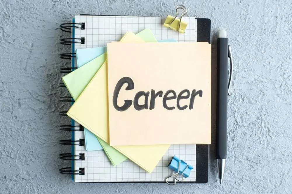 Notebook with grid pattern, pastel sticky notes, and a pen, featuring a prominently displayed note labeled 'Career.'